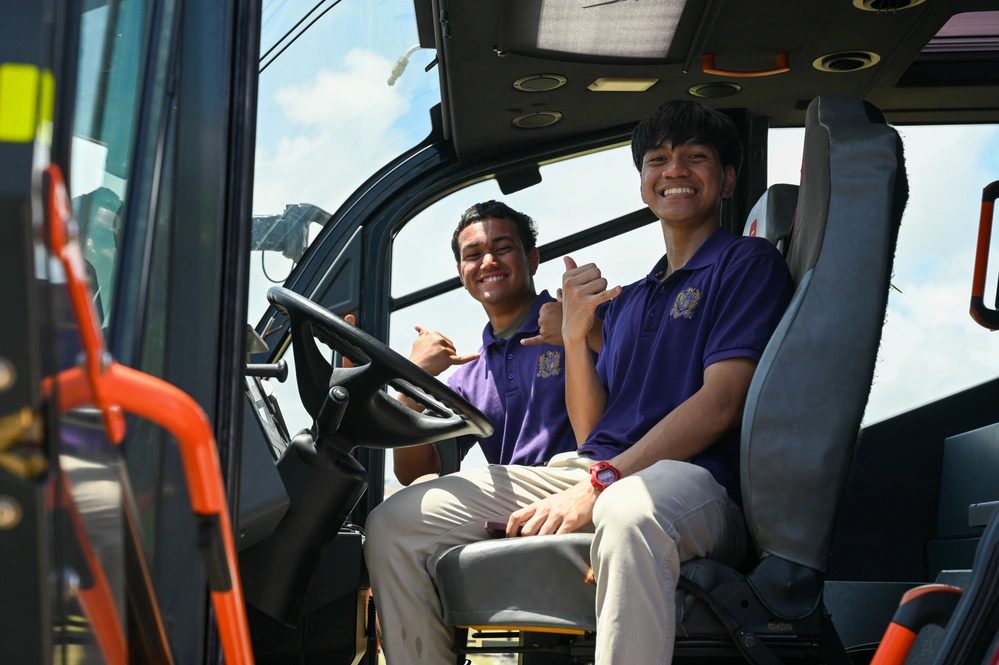 Two students sit in the cab of a fire engine during a department visit